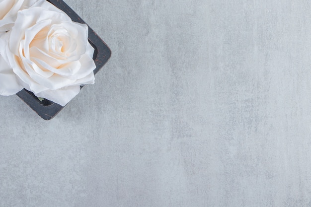 Flowers in a wooden plate, on the white table.