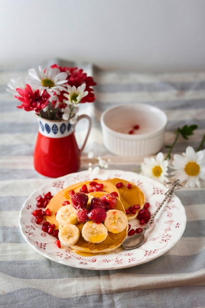Fluffy pancakes with bananas and raspberries on plate