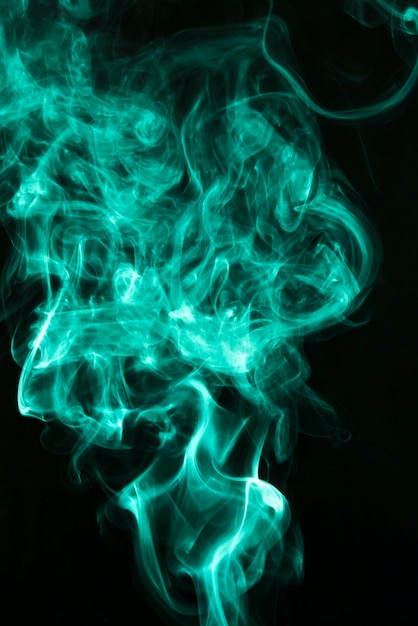 Fluffy puffs of green smoke and fog on black background