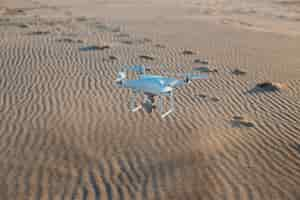 Free photo flying drone landing on sand at beach