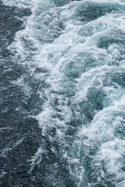 Foamy waves on the surface of the water behind the cruise ship