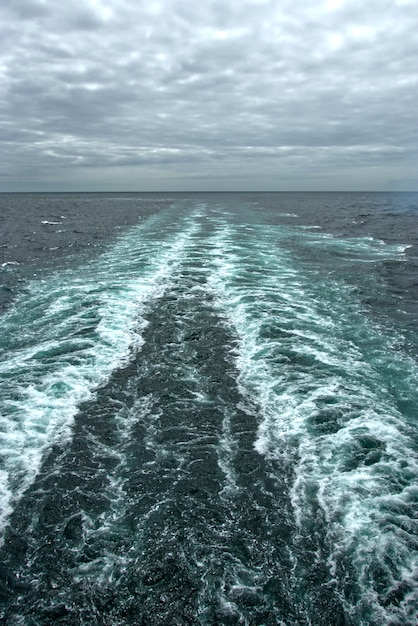 Foamy waves on the surface of the water behind the cruise ship