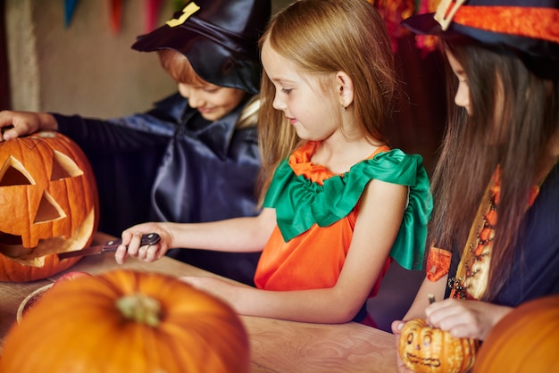 Free photo focus children carving some shapes on the pumpkin