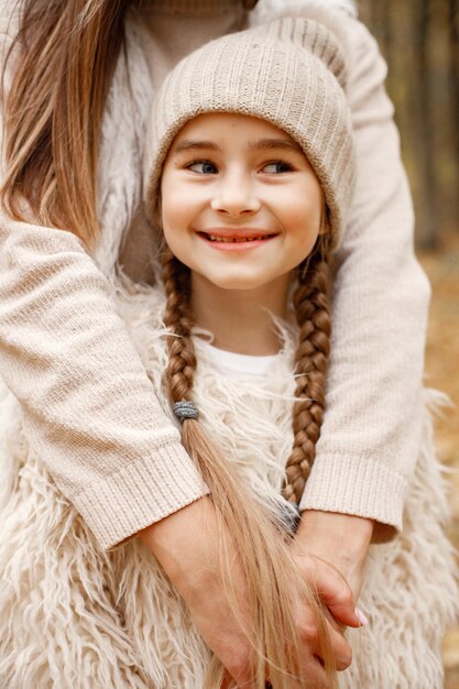 Focus on a happy girl's face. Woman play with her daughter. Girl wearing beige sweater.