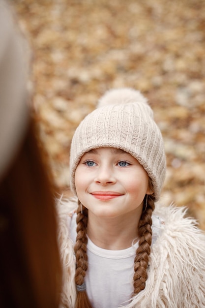 Focus on a happy girl's face. Woman play with her daughter. Girl wearing beige sweater.