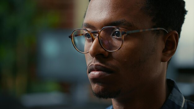 Focus on moving eyes of software developer writing code in front of monitor working focused looking at computer screen. Portrait of software developer with glasses reading algorithm.