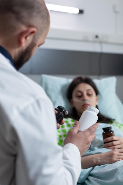 Concentrarsi sulla bottiglia di farmaci da prescrizione somministrata dal medico al paziente in via di guarigione dopo l'intervento chirurgico. medico che presenta un trattamento alternativo alla donna con bassa saturazione di ossigeno.