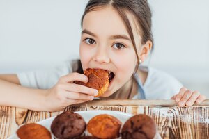 Focus at small girl bites cupcakes