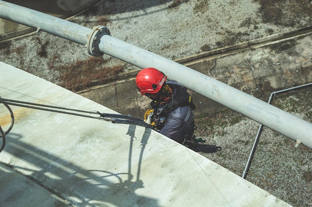 Focus top view male worker down height tank rope access safety inspection of thickness storage oil and gas tank industry