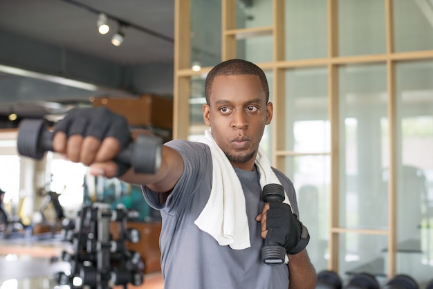 Focused black man holding dumbbells and boxing