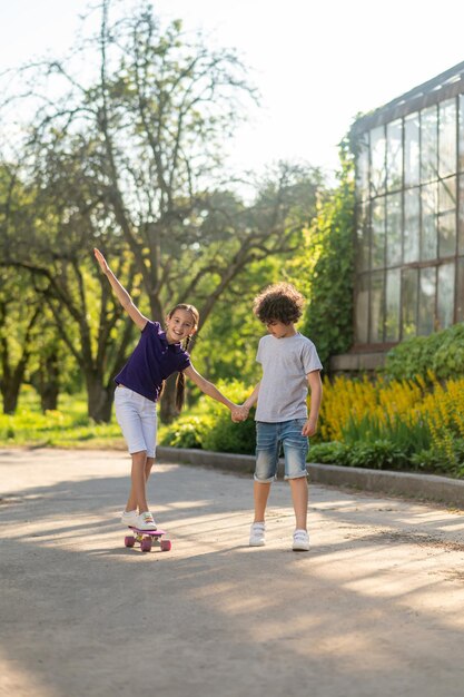 スケートボード中に彼の笑顔の友人をサポートする集中少年