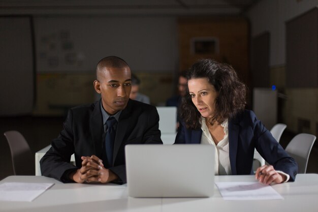 Focused business partners looking at laptop in office