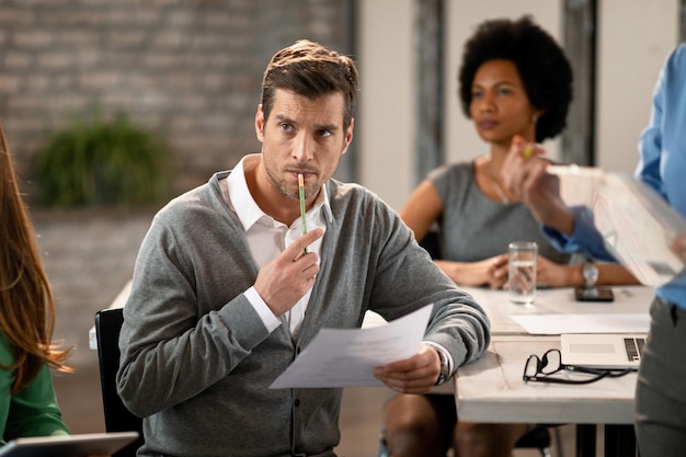 Focused businessman listening a presentation while being in board room with his colleagues Free Photo