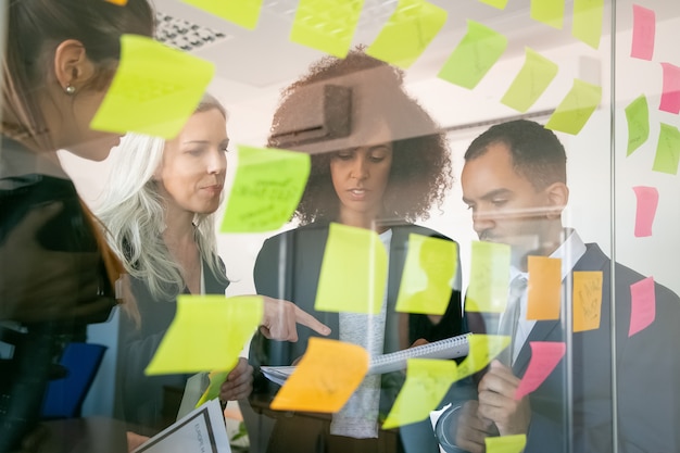 Focused businesspeople reading documents and examining information. Successful concentrated employers in suits meeting in office room and studying reports. Teamwork, business and management concept