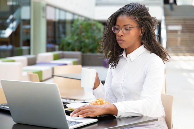 Free photo focused businesswoman drinking coffee while working