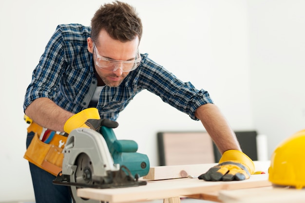 focused carpenter sawing wood board