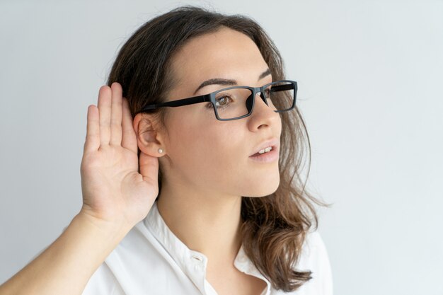 Focused curious office girl in glasses eavesdropping. 