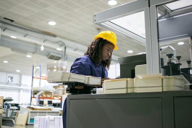 免费照片集中女纸工厂员工戴安全帽,操作工业机器,站在控制板