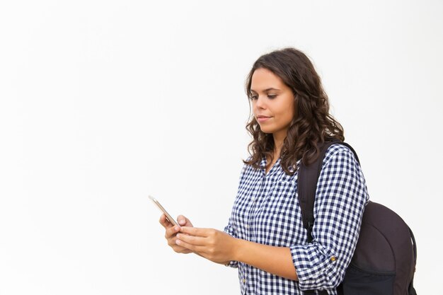 Turista femminile focalizzato con zaino e cellulare