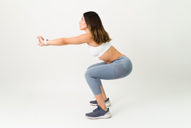 Foto gratuita concentrato sulla fine della mia routine di allenamento. donna sportiva in abbigliamento sportivo che fa esercizi di squat per rafforzare il suo corpo tonico e snello