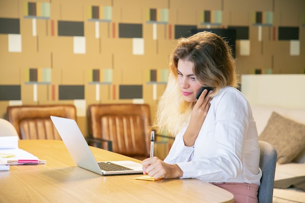 Focused freelancer discussing project with customer on phone