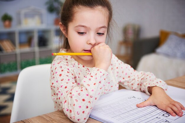 Сосредоточенная девушка делает домашнее задание дома