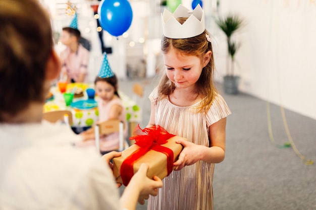 Focused girl in white crown taking gift