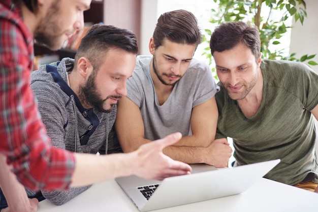 Focused group of men sitting in front of the laptop