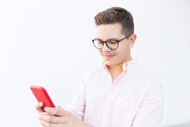 Focused guy in eyeglasses using smartphone