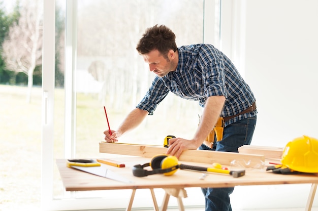 Free photo focused man measuring wooden planks