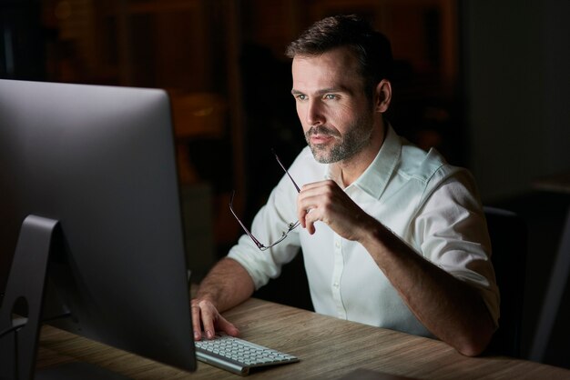 Сосредоточенный человек, использующий компьютер в ночное время