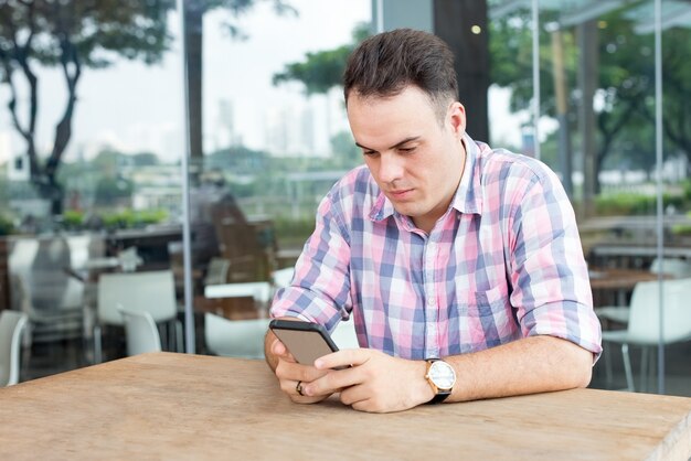 屋外のカフェでスマートフォンを使用する集中した男