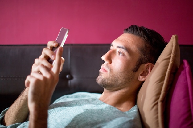 Focused Man Using Smartphone on Sofa in Evening