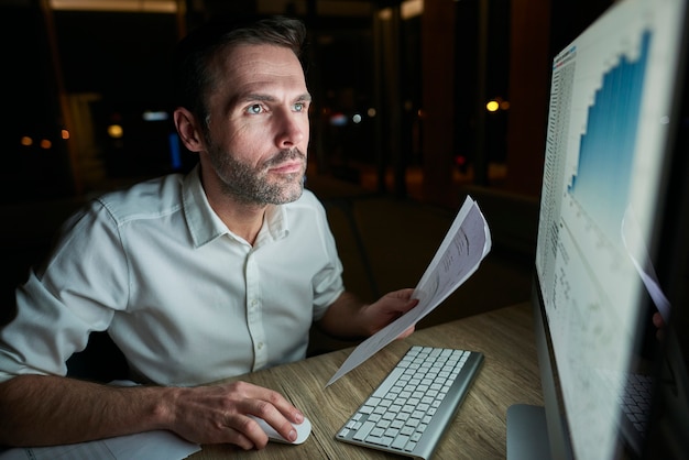 Free photo focused man with document using computer