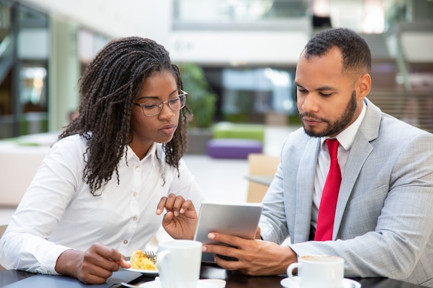 Focused mix raced colleagues watching content on tablet