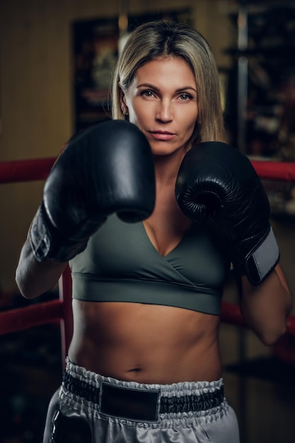 Бесплатное фото Сосредоточенная мускулистая женщина тренируется по боксу в боксерских перчатках.