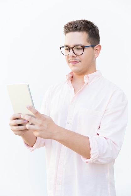 Focused nerdy guy in eyeglasses reading or watching content