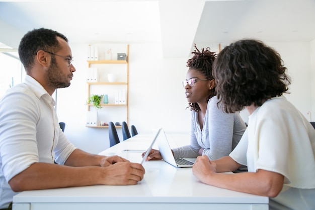 Focused office colleagues talking