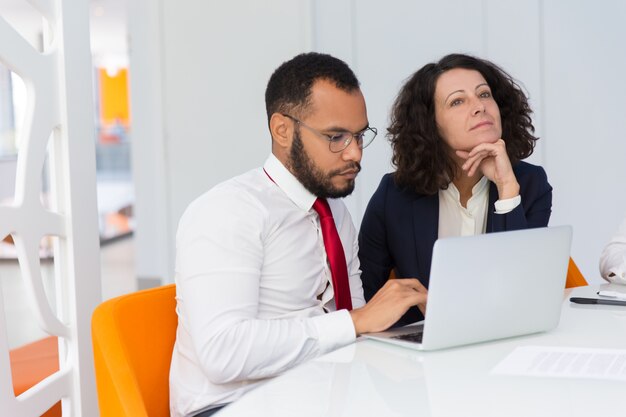 Focused pensive coworkers working on project together