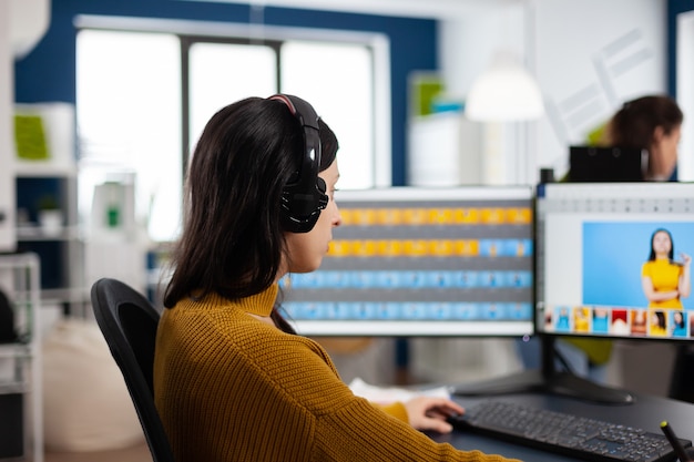 Focused retoucher specialist working at computer in creative office environment wearing headset