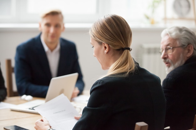 Free photo focused serious businesswoman reading document at group meeting or negotiations