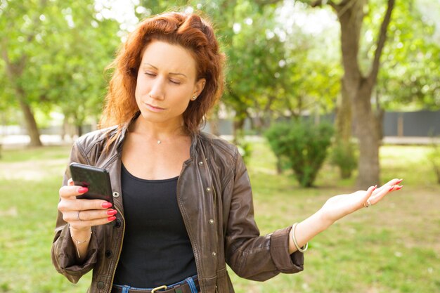 スマートフォンメッセージを読んで焦点を当てた深刻な女性