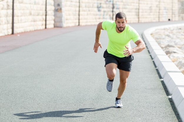 Focused Strong Sporty Man Running Fast on Road