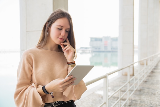 屋外のタブレットコンピューターでブラウズ集中の十代の少女