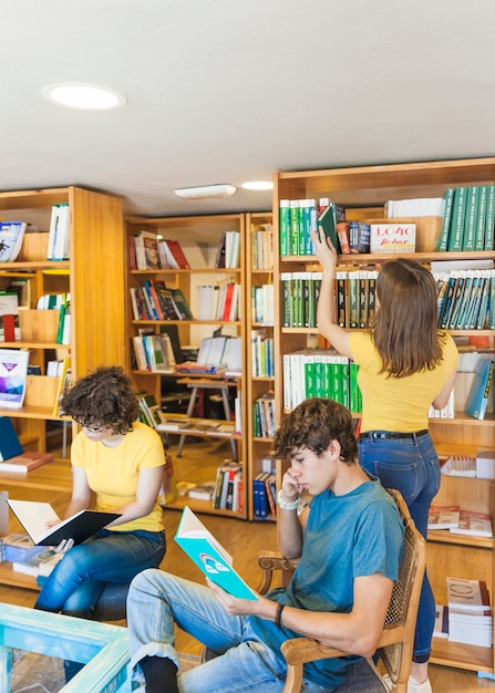 Focused teenagers reading near friend