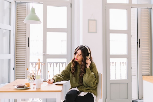 Focused woman drawing and listening to music