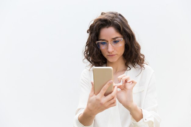 Focused woman in glasses texting message, consulting internet