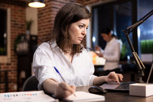 focused woman writing notes at her desk