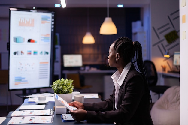 Focused workaholic african american businesswoman working at company financial charts presentation