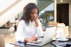 Free photo focused young female office worker working in coffee shop